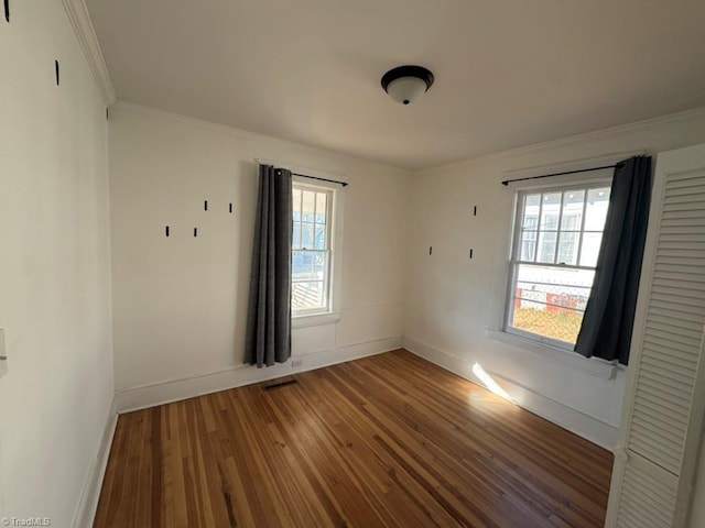 empty room featuring crown molding, hardwood / wood-style floors, and a healthy amount of sunlight