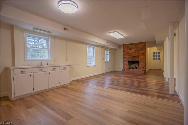 804 W 4th Ave, Lexington, NC 27292 - unfurnished living room with visible vents, baseboards, a fireplace, a sink, and light wood-type flooring