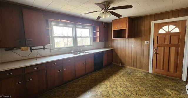 kitchen with dishwasher, sink, ceiling fan, and wood walls