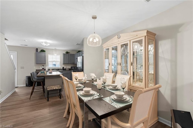 dining room with baseboards, an inviting chandelier, and wood finished floors