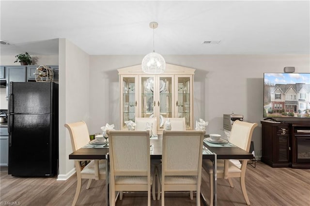 dining space featuring visible vents, baseboards, and wood finished floors