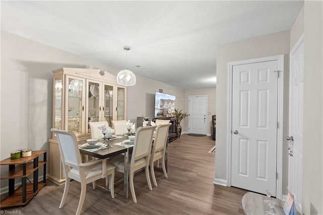 dining room with an inviting chandelier, dark wood-style floors, and baseboards