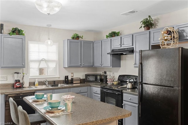 kitchen with visible vents, gray cabinetry, under cabinet range hood, black appliances, and a sink