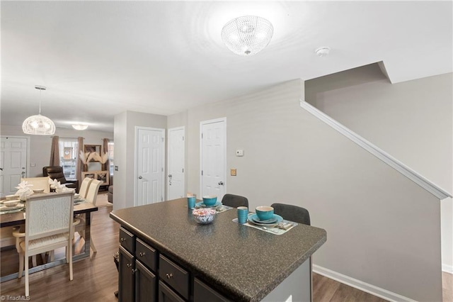 kitchen featuring dark countertops, baseboards, dark wood-style flooring, and a center island