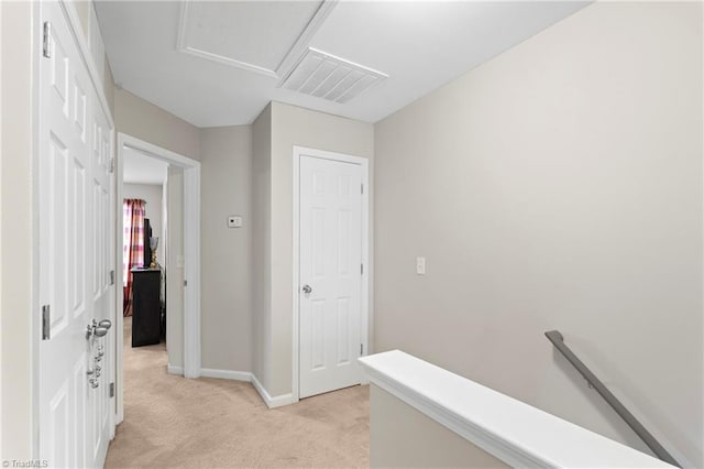 hallway featuring visible vents, baseboards, attic access, an upstairs landing, and light colored carpet