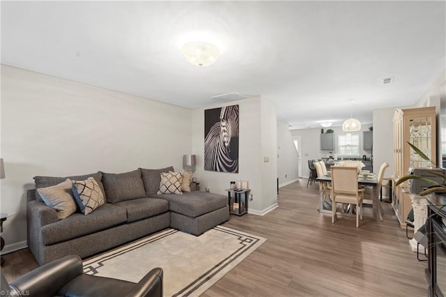 living room with visible vents, baseboards, and light wood-style floors