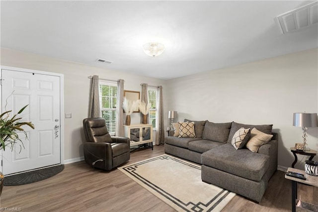 living area featuring visible vents, light wood-type flooring, and baseboards