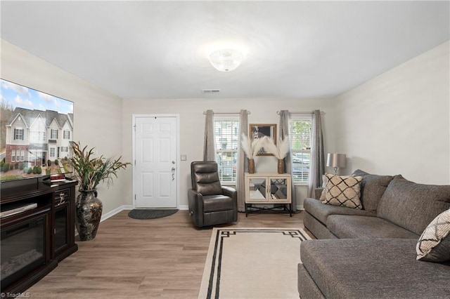 living area with light wood-type flooring, visible vents, and baseboards