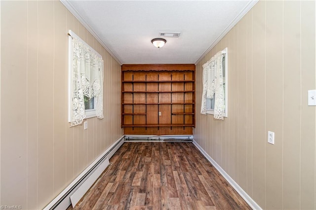 hallway featuring a baseboard radiator, dark wood-style flooring, ornamental molding, plenty of natural light, and wood walls