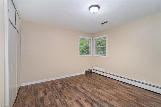 unfurnished room with a baseboard heating unit, wood finished floors, a textured ceiling, and baseboards