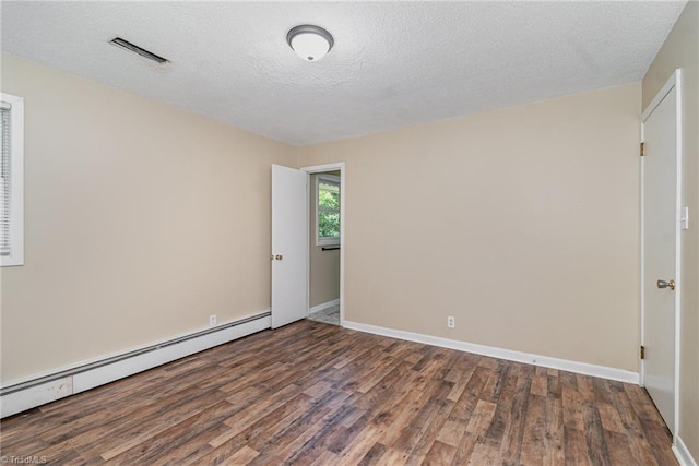 empty room with a baseboard heating unit, wood finished floors, a textured ceiling, and baseboards