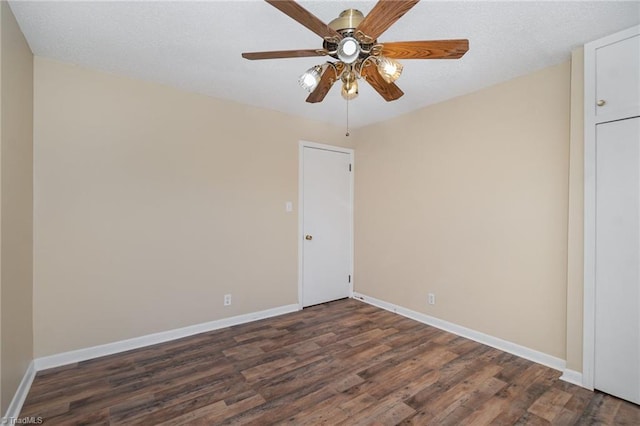 unfurnished room with ceiling fan, dark wood finished floors, and baseboards