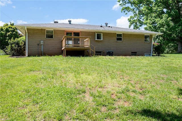 rear view of house with a wooden deck and a lawn