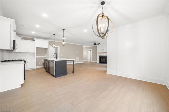 6957 Orchard Path Dr, Clemmons, NC 27012 - kitchen with open floor plan, a chandelier, appliances with stainless steel finishes, white cabinetry, and ornamental molding