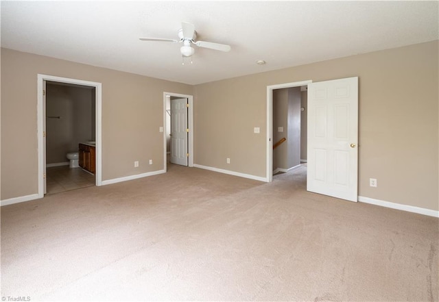 unfurnished bedroom featuring ceiling fan, light colored carpet, and ensuite bath