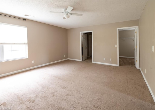 unfurnished bedroom featuring a spacious closet, light carpet, ceiling fan, and a closet