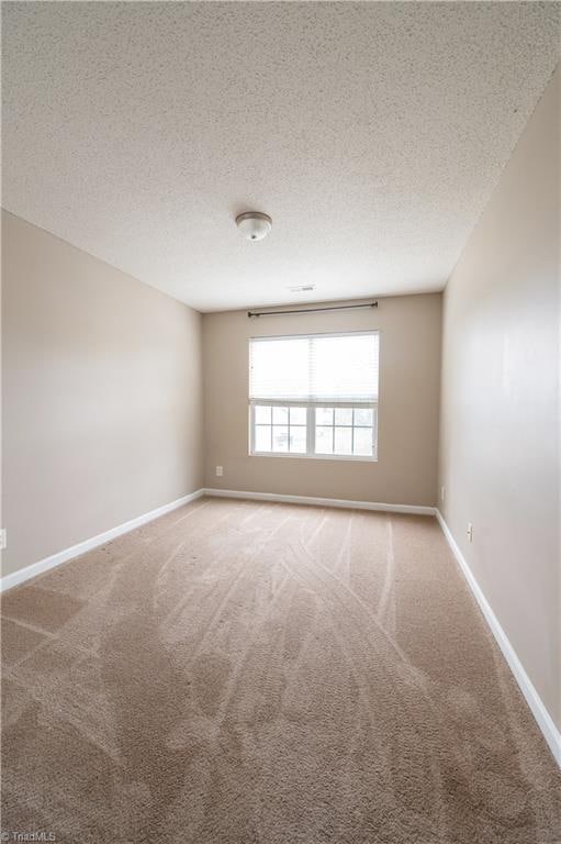 empty room with a textured ceiling and carpet floors