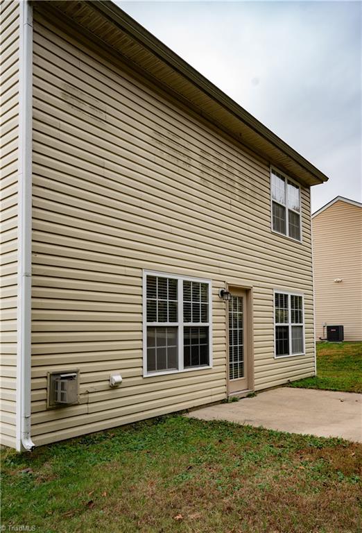 back of house featuring a lawn, central AC, a wall mounted AC, and a patio area