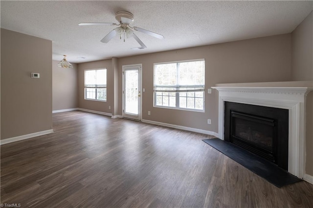 unfurnished living room featuring dark wood-type flooring, a textured ceiling, and ceiling fan