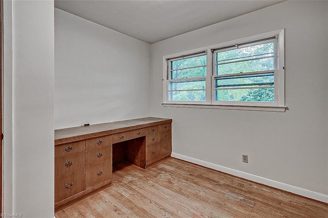 unfurnished office featuring light hardwood / wood-style flooring and built in desk