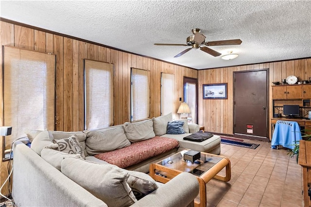 living area featuring wood walls, ceiling fan, crown molding, a textured ceiling, and light tile patterned flooring