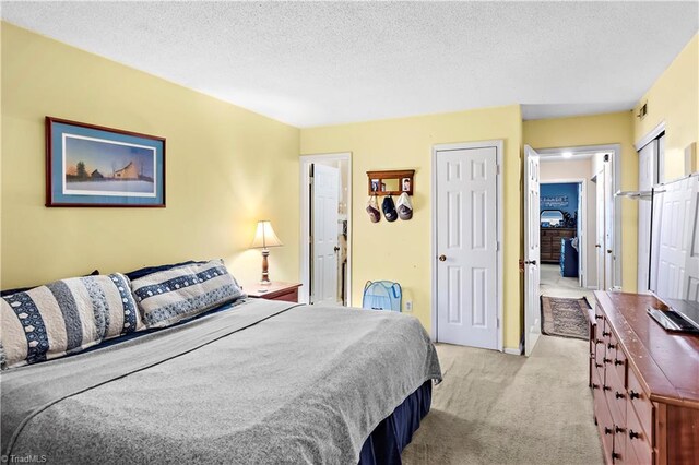 bedroom with light colored carpet and a textured ceiling