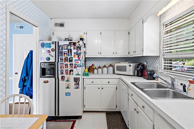 kitchen with white appliances, a sink, wallpapered walls, white cabinets, and light countertops