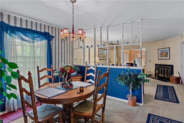 dining area featuring a chandelier, carpet flooring, and a fireplace with flush hearth