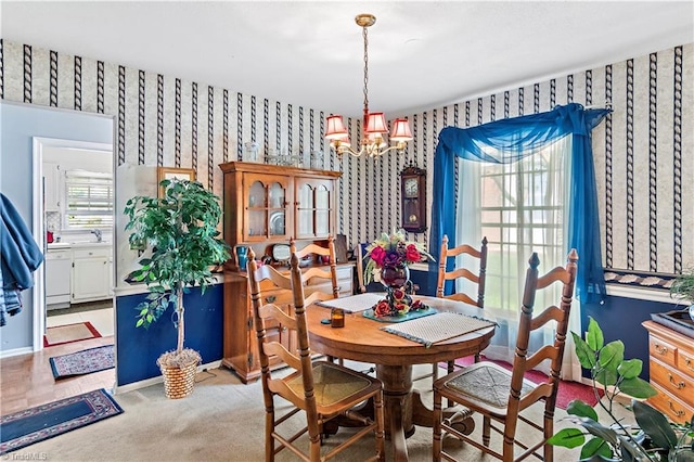 dining room featuring wallpapered walls, a chandelier, baseboards, and light carpet