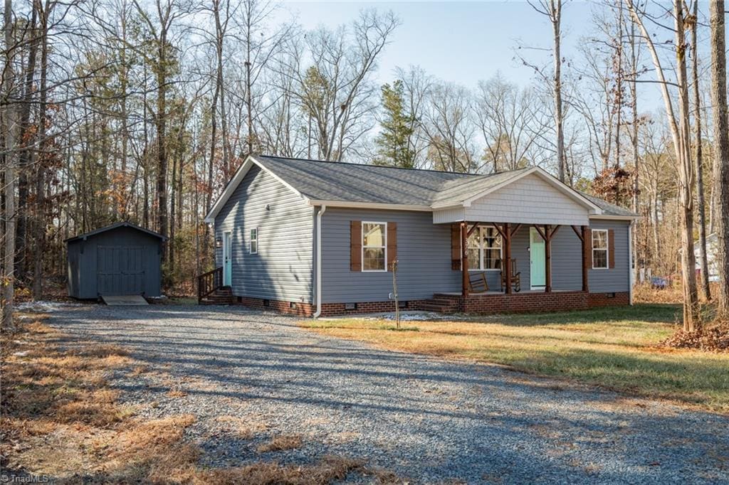 ranch-style home featuring a porch, a storage unit, and a front yard