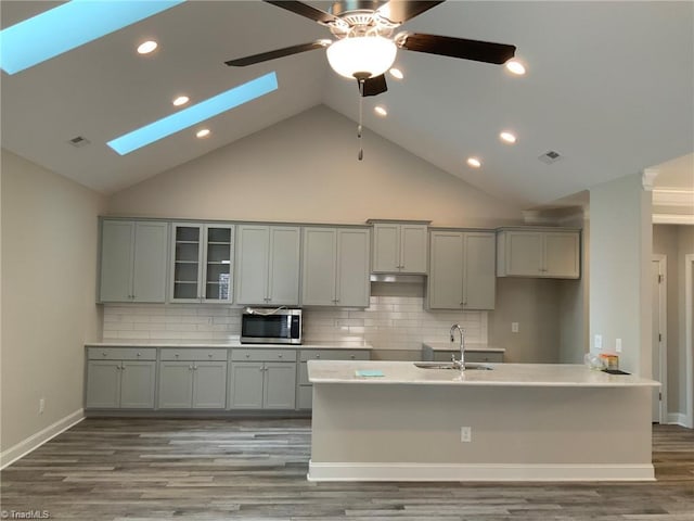 kitchen featuring gray cabinetry, a skylight, a sink, visible vents, and stainless steel microwave