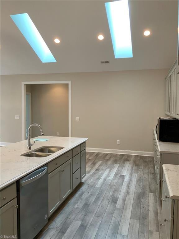 kitchen with light wood finished floors, appliances with stainless steel finishes, a sink, and gray cabinetry