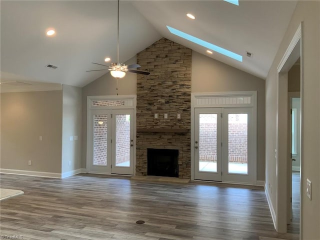 unfurnished living room with a skylight, visible vents, and wood finished floors