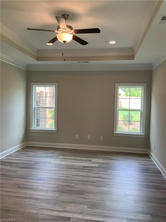 spare room with a raised ceiling, visible vents, and wood finished floors