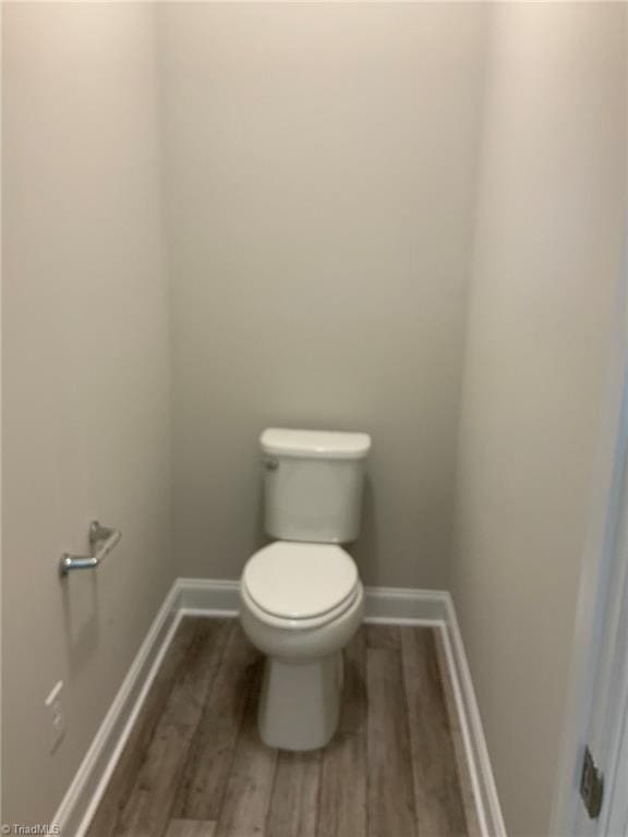 bathroom featuring toilet, baseboards, and wood finished floors