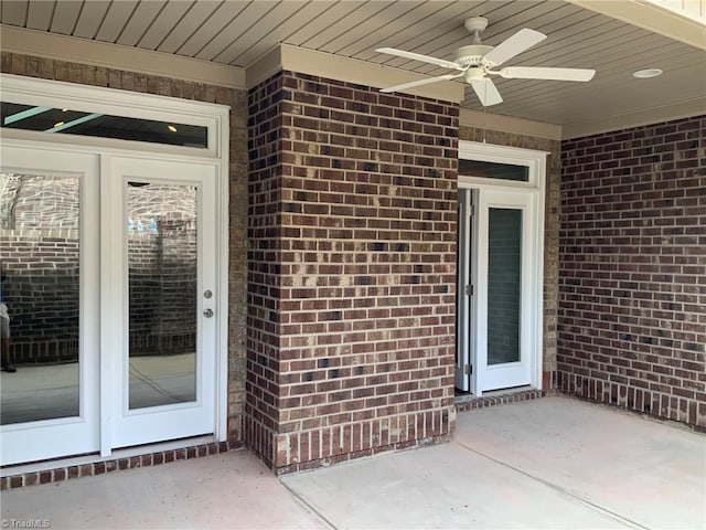 view of exterior entry featuring a ceiling fan and brick siding