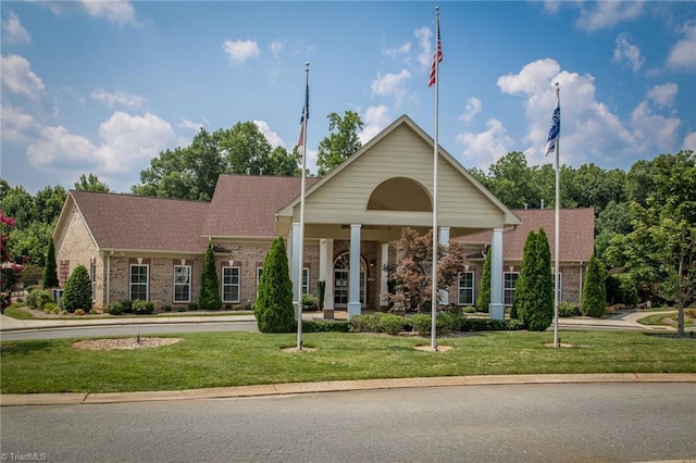 view of front of property with brick siding, roof with shingles, and a front yard