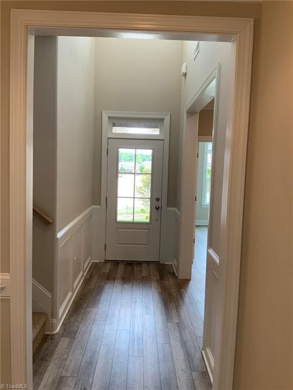 entryway featuring hardwood / wood-style floors, stairway, wainscoting, and a decorative wall