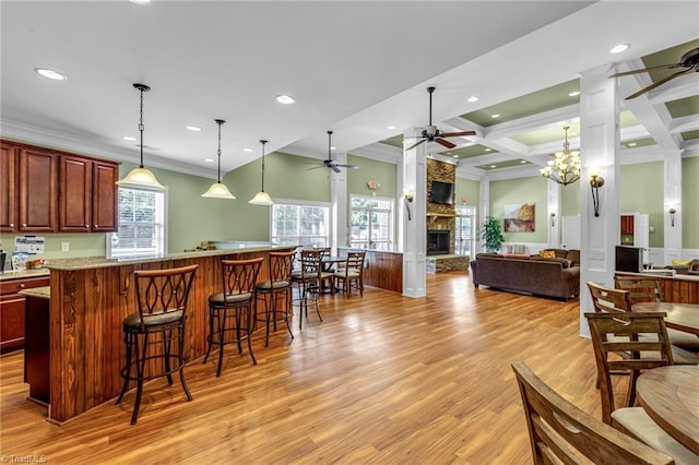 kitchen with coffered ceiling, a breakfast bar area, light wood-style floors, a fireplace, and beam ceiling