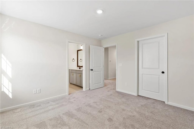 unfurnished bedroom featuring ensuite bath and light colored carpet