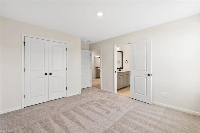 unfurnished bedroom with ensuite bathroom, a closet, and light carpet