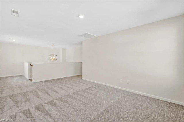 carpeted spare room featuring a notable chandelier