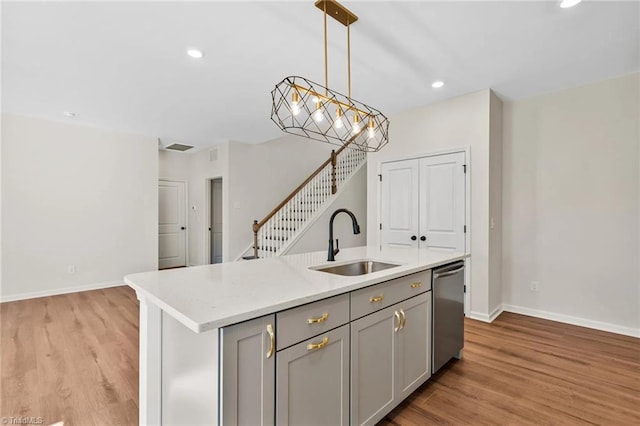 kitchen featuring gray cabinetry, dishwasher, pendant lighting, a kitchen island with sink, and sink