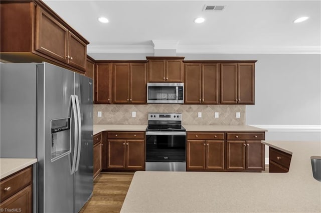 1604 Sunny Hill Way, Colfax, NC 27235 - kitchen with appliances with stainless steel finishes, crown molding, light countertops, wood finished floors, and backsplash