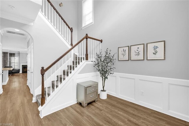 1604 Sunny Hill Way, Colfax, NC 27235 - stairway with arched walkways, wood finished floors, a wainscoted wall, a decorative wall, and a fireplace