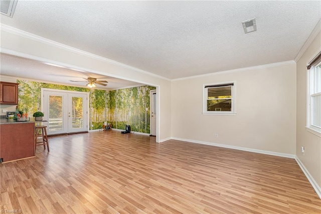 unfurnished living room featuring light wood-type flooring, french doors, a textured ceiling, ceiling fan, and ornamental molding