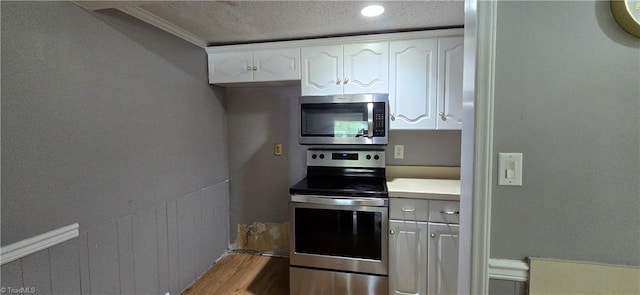 3613 Mcconnell Rd, Greensboro, NC 27405 - kitchen with stainless steel appliances, white cabinetry, wood finished floors, light countertops, and a textured ceiling