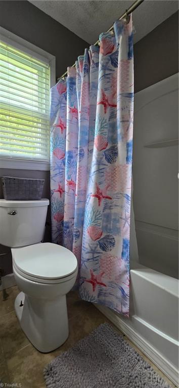 3613 Mcconnell Rd, Greensboro, NC 27405 - bathroom with shower / tub combo, a textured ceiling, and tile patterned floors