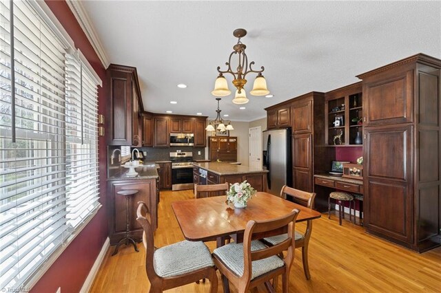dining room with an inviting chandelier, ornamental molding, light wood-style floors, and plenty of natural light