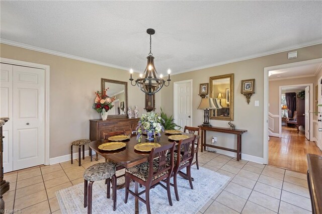 dining area with a textured ceiling, a notable chandelier, ornamental molding, and light tile patterned floors